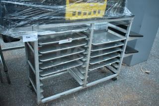 Metal commercial double pan transport rack with commercial casters, containing multiple trays, wrapped in plastic.