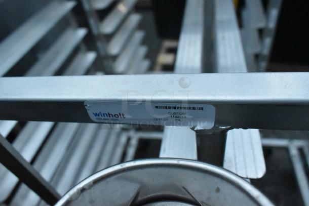 Metal commercial double pan transport rack with commercial casters, label marked "Winholt, 12/11/23, Custom, 1142913".
