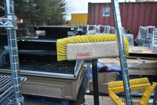 Gray poly trash can containing wire shelf and cleaning brushes. Brushes have yellow bristles and red logo marking.