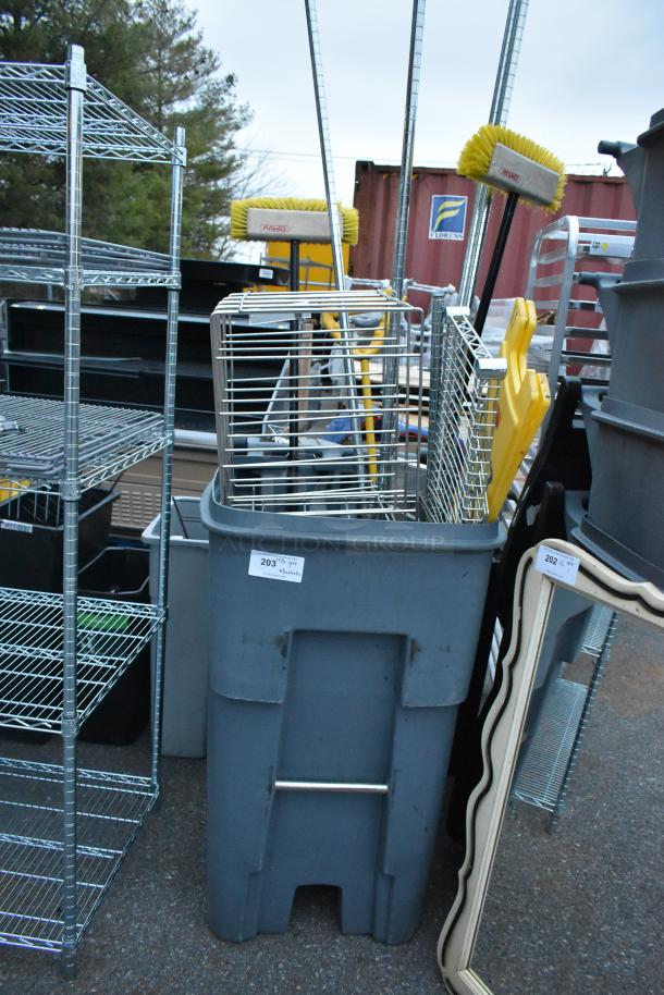 Gray poly trash can containing wire shelf, brooms, and cleaning supplies. Label reads "203" for identification. Sturdy condition.