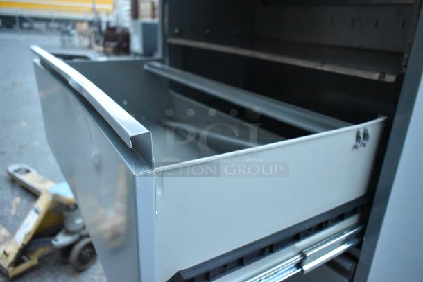 Gray metal filing cabinet with four drawers and one door, in good condition. Open drawer shows spacious interior.