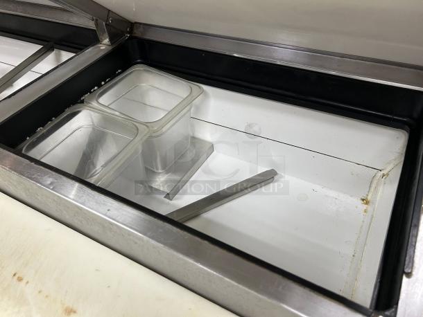 True TPP-AT-67-HC pizza prep table with refrigerated base, shown open, includes clear storage bins and metal divider.