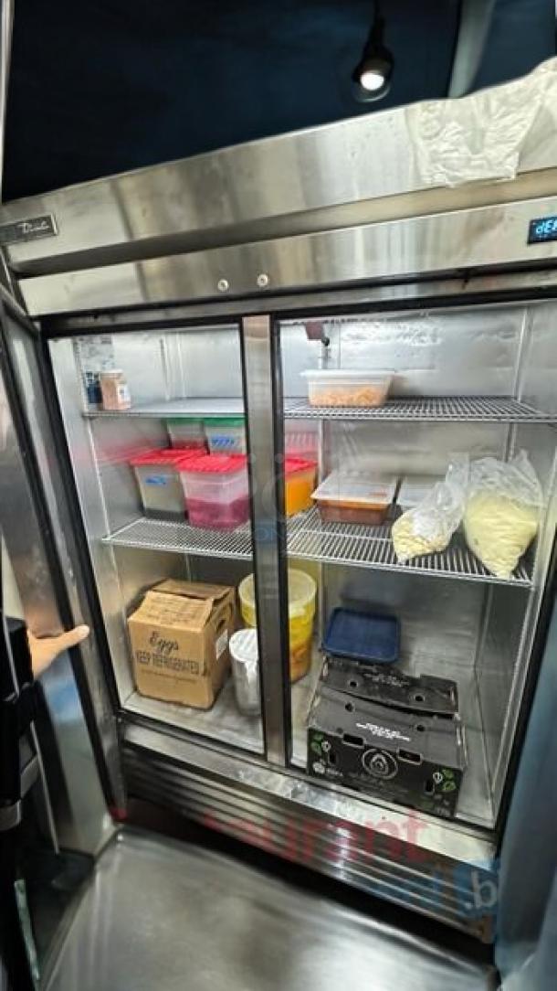 True T-49-HC Reach-In Refrigerator, immaculate condition, stainless steel, double doors, interior shelving with assorted items.