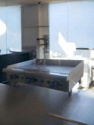 Commercial stainless steel flat top griddle in pristine condition, fully tested, with control knobs and durable construction.