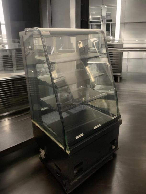 Curved glass refrigerated bakery/display case with multiple shelves, black base, superior condition, fully operational.