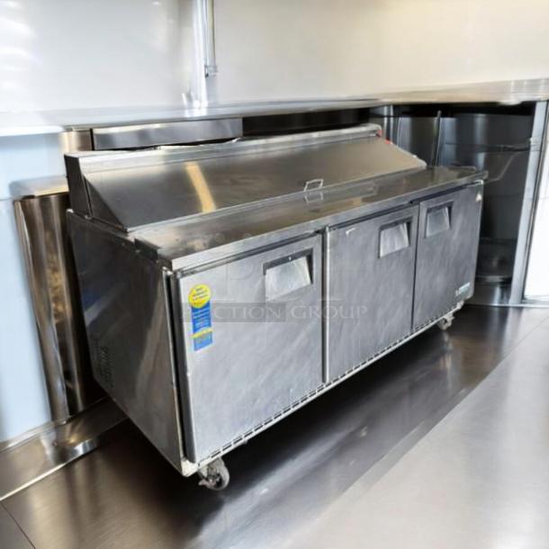 Continental Refrigerator sandwich prep table in top-tier condition, featuring three doors, stainless steel finish, and casters.