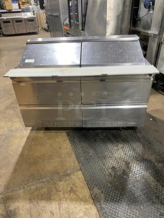 Stainless steel Welbilt/Delfield commercial refrigerated prep table, model D4460NP-24M, with four drawers and cutting board.