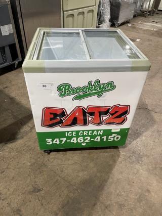 Commercial chest freezer merchandiser with sliding glass doors, branded "Brooklyn Eatz Ice Cream." Features 110V power, good condition.