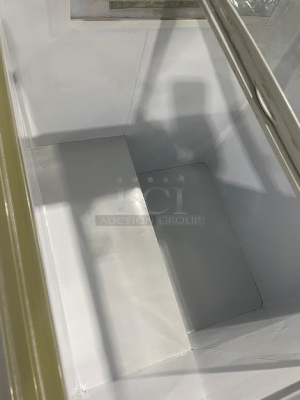 Commercial reach-down chest freezer with two sliding transparent doors, 110V. Clean interior, minimal wear. Ideal for merchandising.