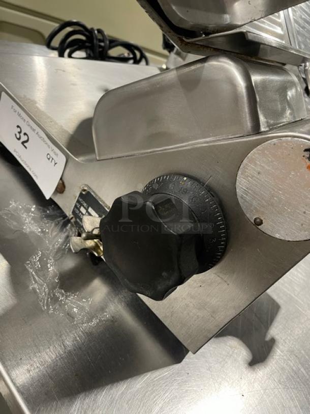 Heavy duty commercial countertop deli meat slicer in stainless steel, featuring an adjustable black knob. Auction label marked "32".