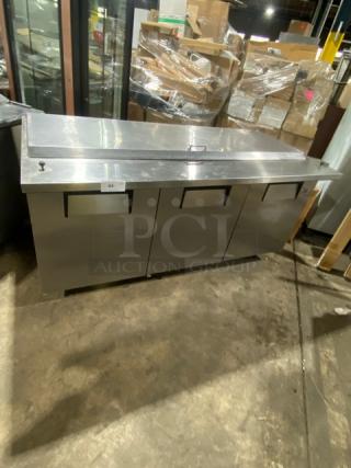 True commercial refrigerated pizza prep table, model QA7230MB, with three-door storage, all stainless steel. Serial 14509450.