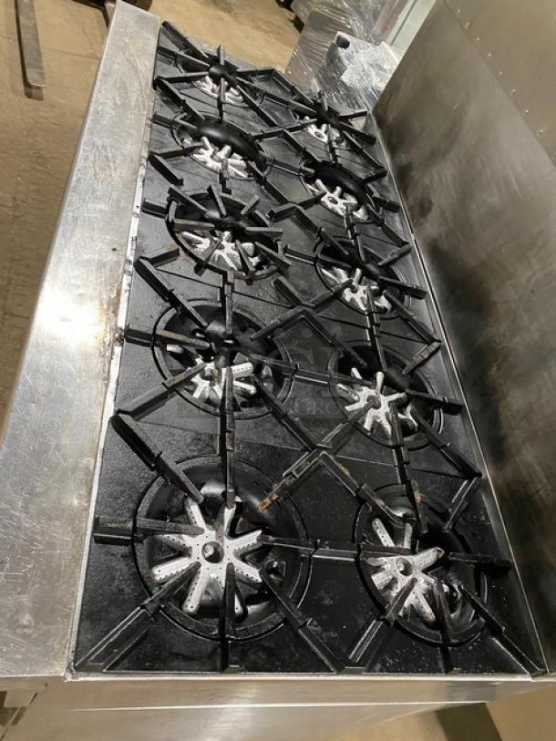 Garland H2S4 stove with 10 burners, raised backsplash, 2 ovens beneath, stainless steel, on casters, model info visible.