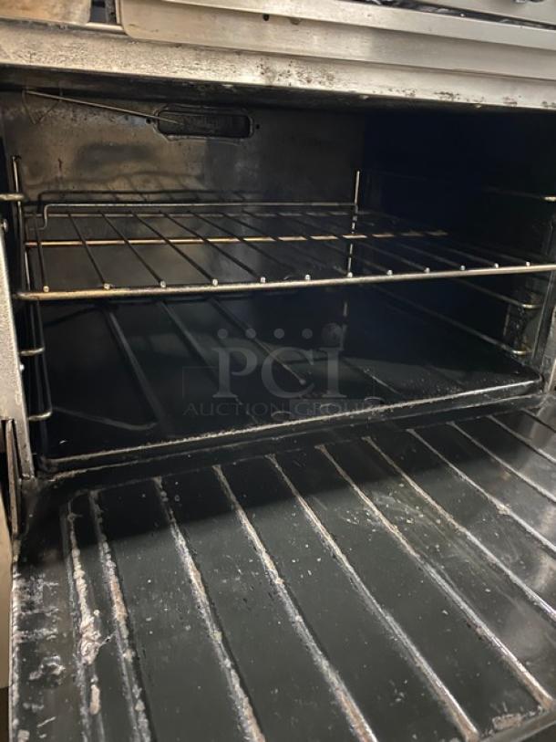 Garland commercial 10 burner stove, Model H2S4, natural gas, stainless steel, with raised backsplash, dual ovens, on casters.