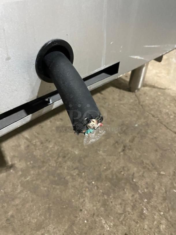 Damaged power cord of Cookline commercial induction range; frayed wires visible, indicating repair needed. Stainless steel finish.
