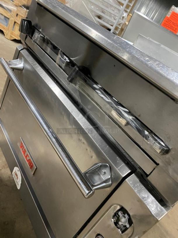 Vulcan commercial 6-burner gas stove with stainless steel oven, on casters. Features include control knobs and logo.