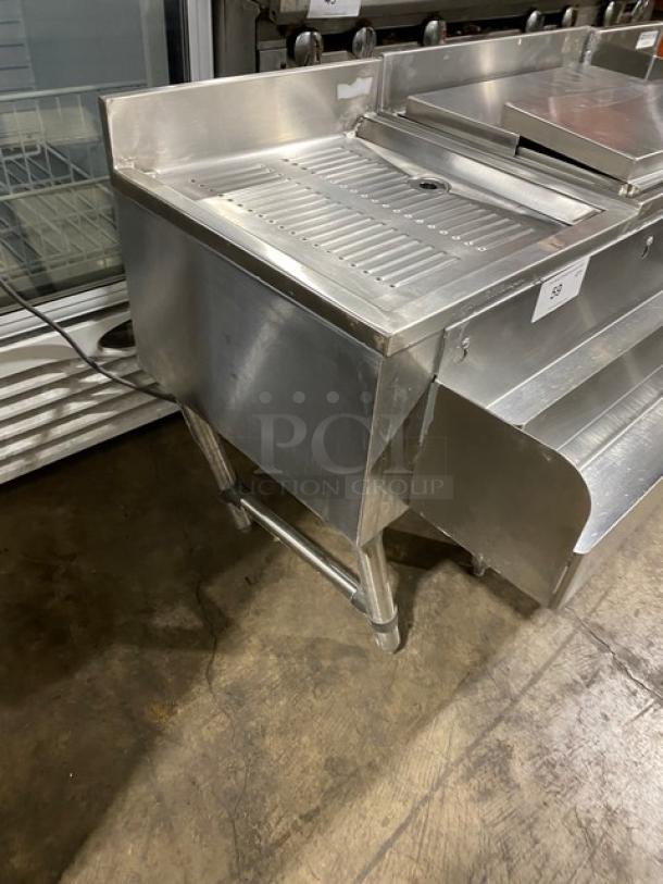 NBR LD1218 stainless steel under-bar sink with left-side draining table and right-side bottle display, on legs.