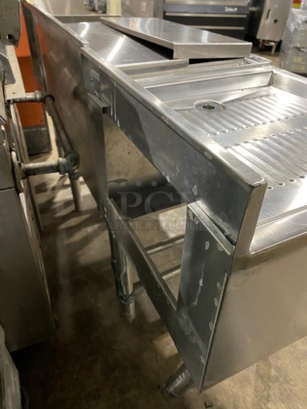 NBR Model LD1218 stainless steel commercial under-bar sink with left-side draining table, right-side bottle display, on legs.