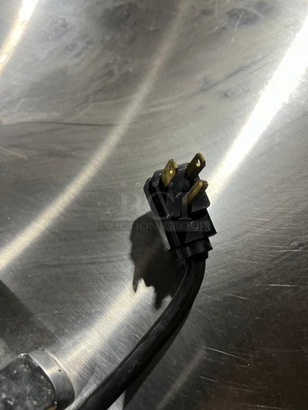 Close-up of power plug for Hoshizaki SR48B18M refrigerated prep table, showcasing three-prong design on stainless steel surface.