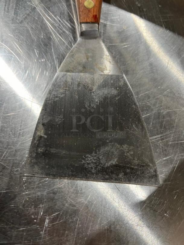 Dexter 4" stiff griddle scraper, model 5254, with a wooden handle. Signs of use visible on blade surface.