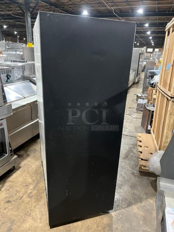 True commercial 2-door reach-in refrigerator, model GDM41. Black side view, sliding view-through doors, 115V 1Phase, in warehouse.