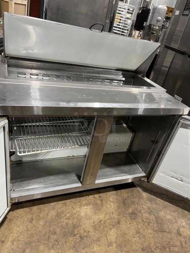 Avantco commercial refrigerated sandwich/salad prep table with stainless steel finish, two-door storage, and 115V, open doors.