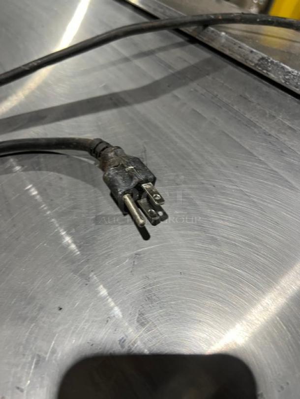 Avantco stainless steel refrigerated prep table, 115V, with two-door storage, plug shown on surface.