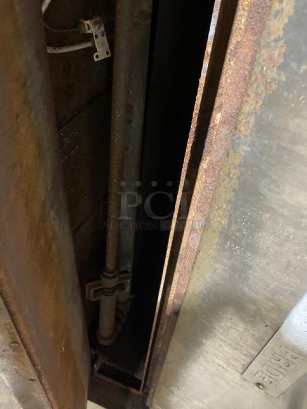 Bakers Pride commercial stainless steel gas-powered pizza oven with visible interior pipes and rust, indicating wear.