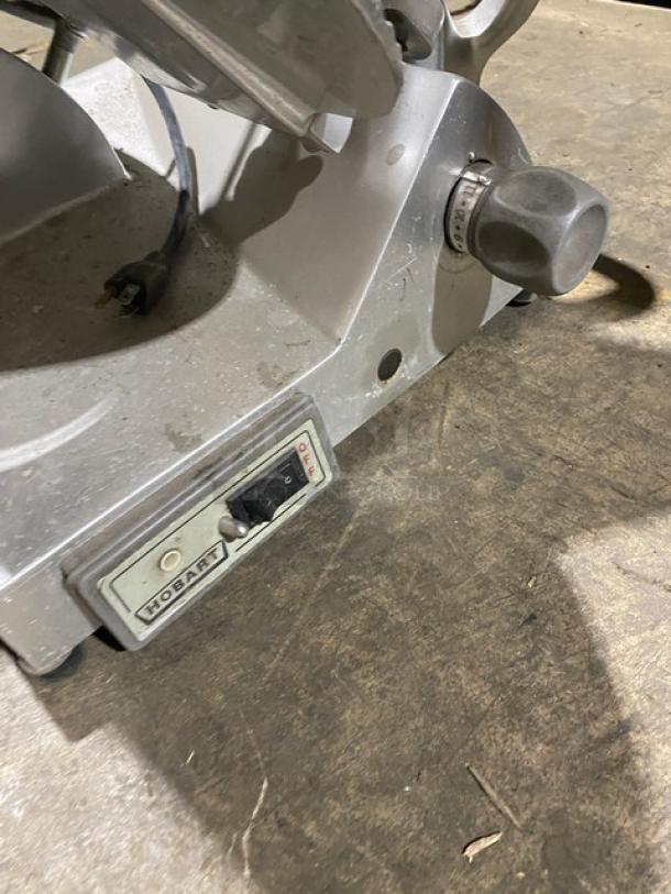 Hobart EDGE commercial meat slicer, electric, 120V, 1 phase, on legs. Serial number 21-1005506 with on/off switch visible.