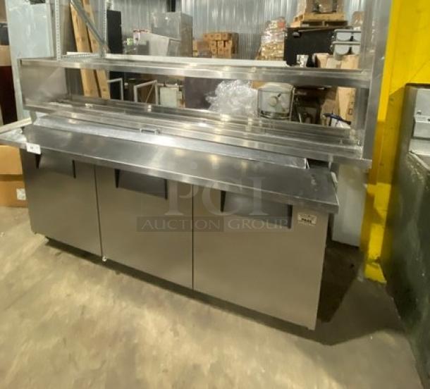 True refrigerated pizza prep table, model QA7230MB, stainless steel, with 3-door storage and overhead serving shelf.