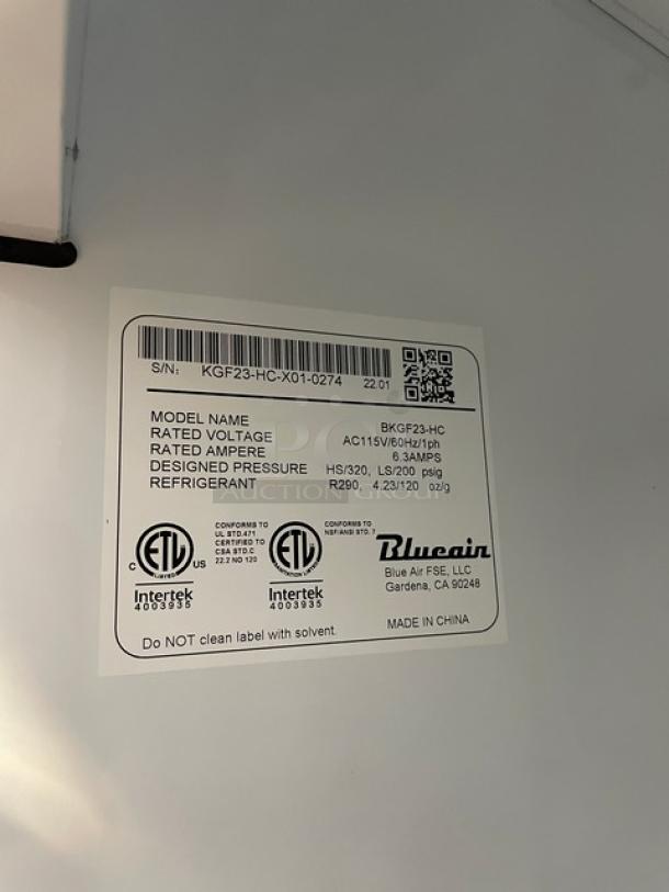 Blue Air glass door freezer, model BKGF23-HC, serial KGF23HCX010274, 115V, on casters. Label shows specs and certifications.