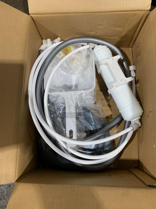 Coiled hoses and white plastic components in a cardboard box, part of Scotsman NS0422A-1B ice machine accessories.