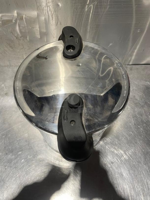 Sitramax 13L pressure cooker with lid and handles, new condition. Polished finish, visible Sitram branding on lid grip.