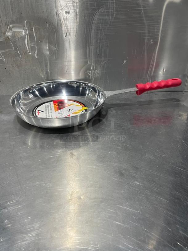Adcraft HER-12FP/4 aluminum frying pan with red rubber grip handle, new condition, label displayed inside.
