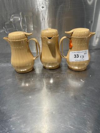 Set of 3 new Service Ideas insulated ABS plastic coffee carafes with push button lids, beige color, lot number tag visible.