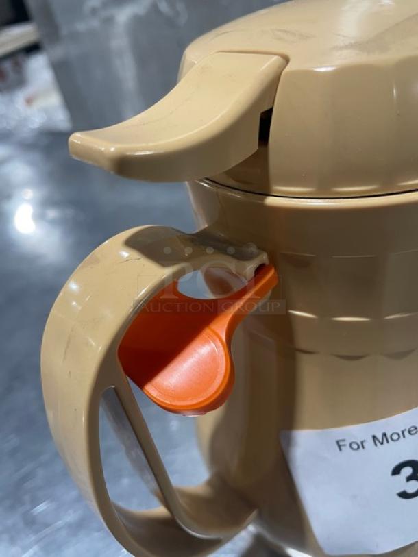 Service Ideas insulated ABS plastic coffee carafe with push-button lid, in new condition. Beige with orange accents.