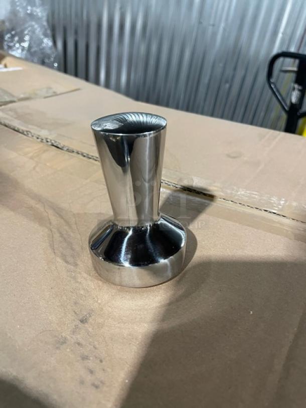 Stainless steel commercial-grade tamper on cardboard, pristine condition, polished finish for professional use.