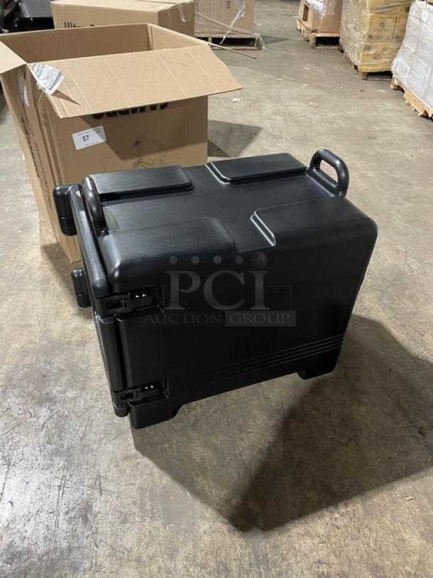 Brand new Cambro Ultra Camcarrier black front-loading insulated hot box/food pan carrier on warehouse floor.