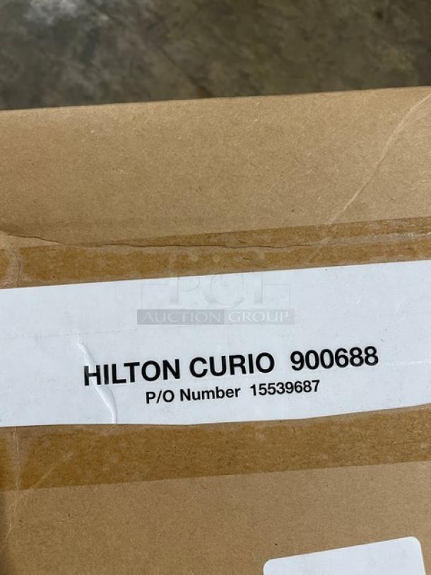 Cardboard box with label reading "HILTON CURIO 900688, P/O Number 15539687." Contains new WineRacks By Marcus wine rack.