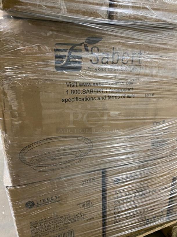 Mixed pallet with various commercial items in original boxes, including Luigi Bormioli glass tumblers and Libbey plates. Boxes are shrink-wrapped and labeled, some with "Sabert" branding and contact details.