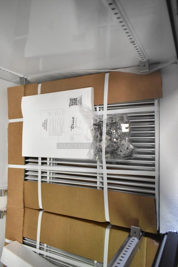 Brand new True GDM-33-HC-LD cooler merchandiser interior, showcasing poly-coated racks, packaging materials, and instruction manual.