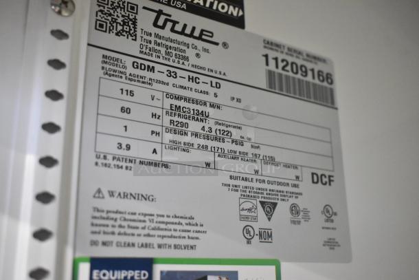 Label on True GDM-33-HC-LD cooler showing model, voltage (115V), refrigerant type (R290), and electrical specs. New condition.