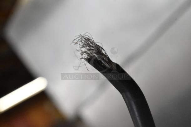 Frayed end of an electrical cable, showing exposed metal wires against a blurred background.