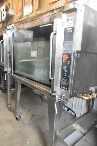 Hardt Inferno 4500 stainless steel rotisserie oven, natural gas, commercial casters, skewers, control panel visible.