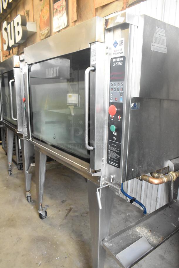 Hardt Inferno 4500 stainless steel commercial rotisserie oven, natural gas powered, with skewers, metal legs, on casters.