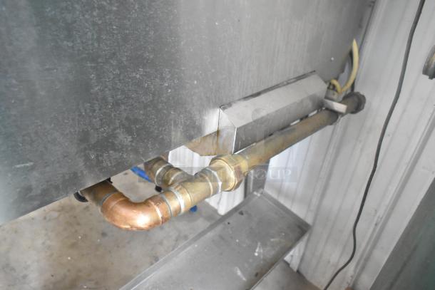 Stainless steel piping and fittings of a Hardt Inferno 4500 rotisserie oven, showing gas connection and part of metal leg.