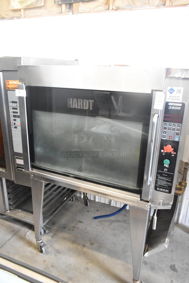 Hardt Inferno 4500 commercial rotisserie oven, stainless steel, natural gas, with skewers, metal legs, and casters.
