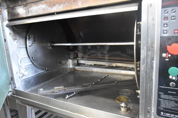 Hardt Inferno 4500 stainless steel commercial rotisserie oven, natural gas powered, with skewers and metal legs on casters.