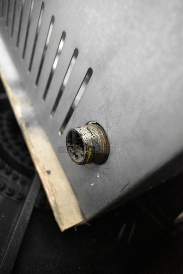 Stainless steel commercial countertop gas burner, single pot range. Slight wear visible on the metal surface, valve connector shown.