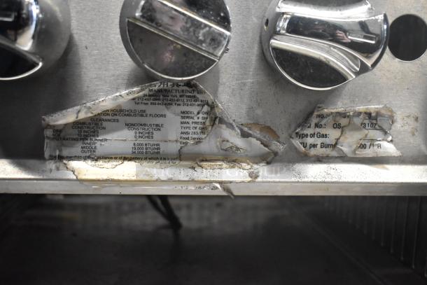 Stainless steel commercial countertop gas burner with control knobs and worn labels showing BTU specifications and gas type.