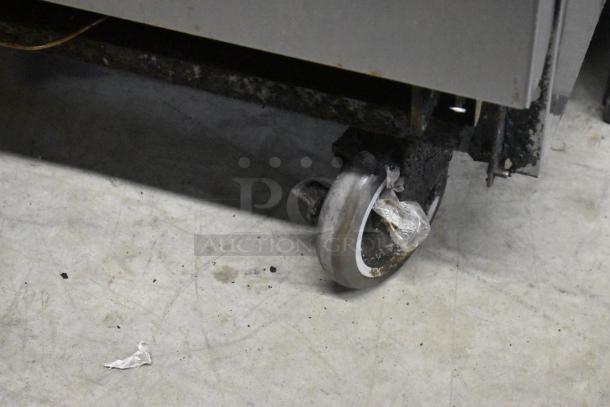 American Range commercial caster wheel detail, part of a stainless steel 6-burner range with oven, showing wear.